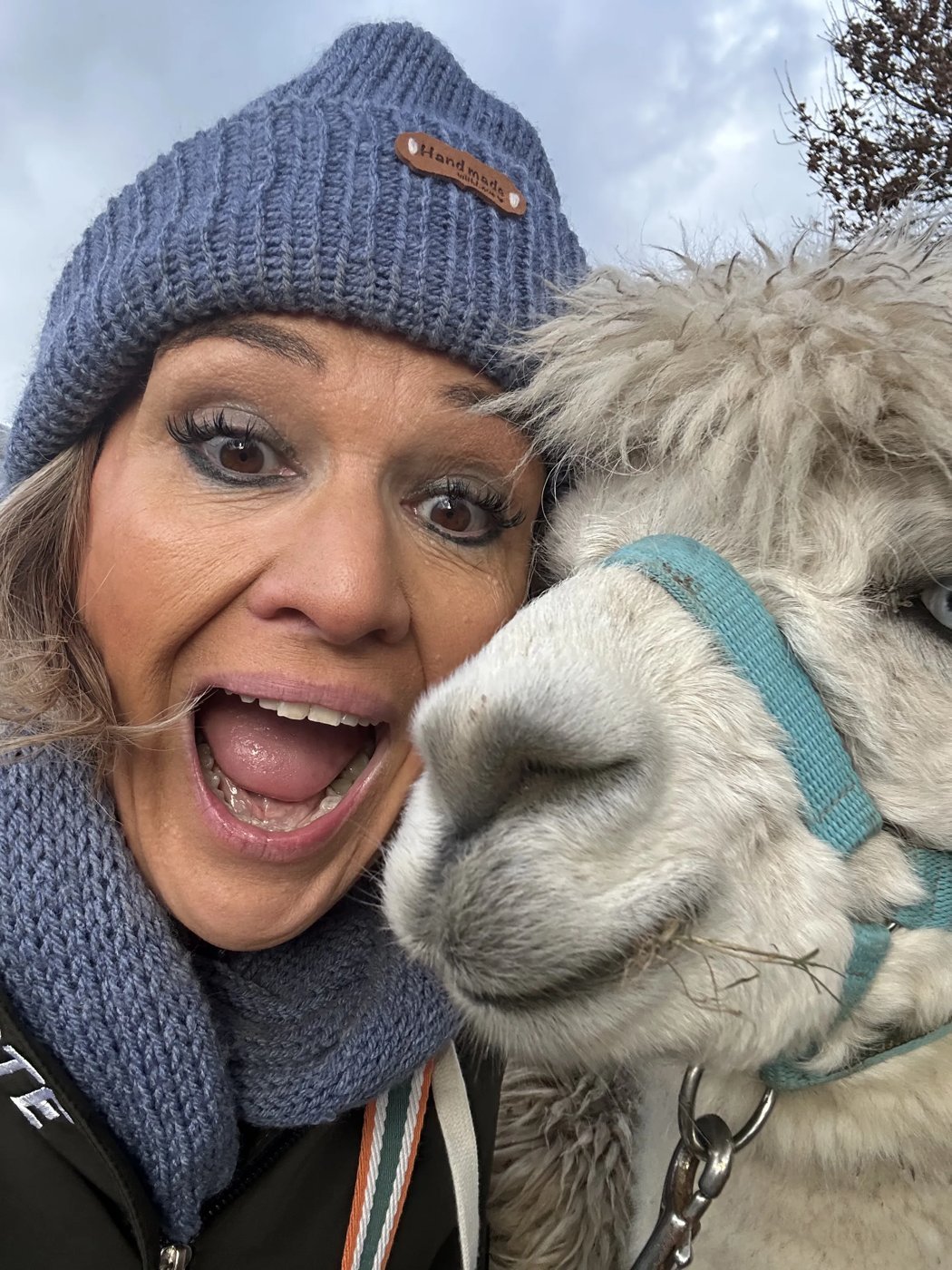 Karen from Done Different pulling a big excited face in a selfie, cheek to cheek with a fluffy llama